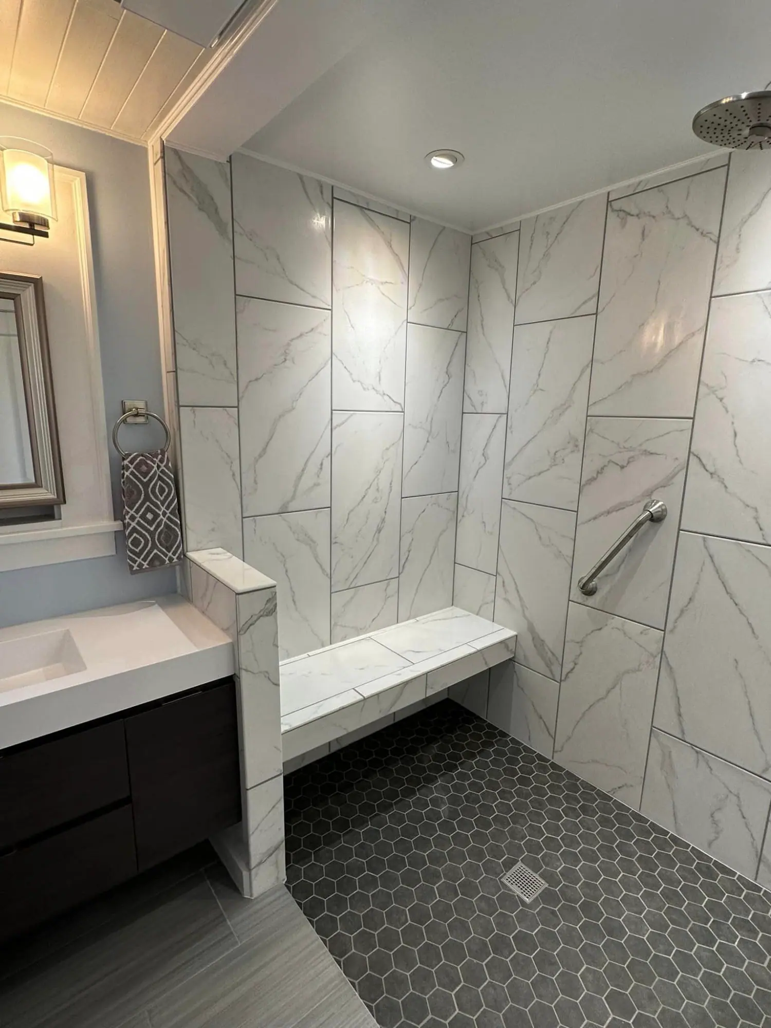 Tiled walk-in shower with a bench and hexagon floor